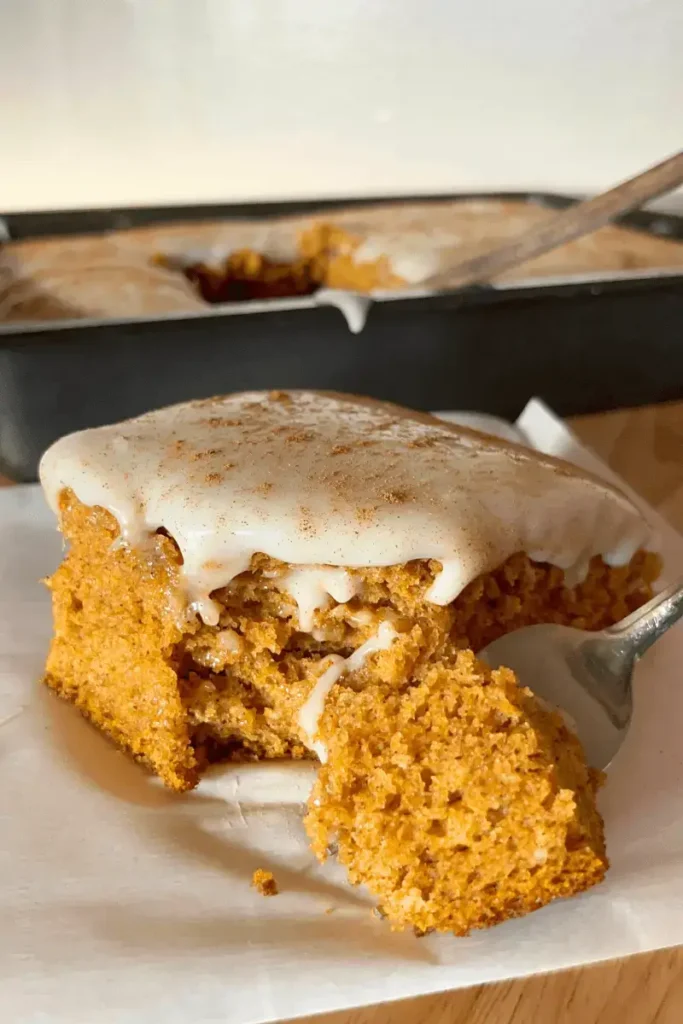 Close-up of sourdough pumpkin spice bar with cream cheese frosting and a bite on a spoon — soft, moist, and full of cozy fall flavor.