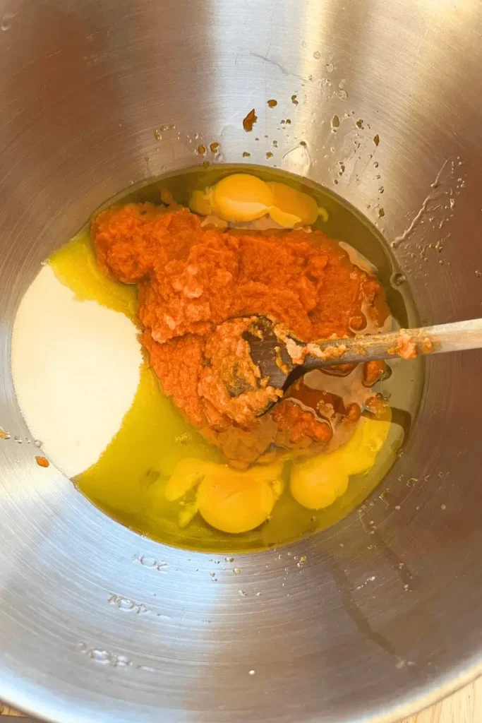 Whisking eggs, sugar, oil, pumpkin purée, and sourdough starter in a bowl — preparing batter for sourdough pumpkin spice bars.