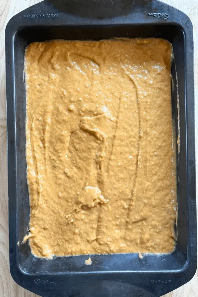 Sourdough pumpkin spice bar batter poured into a greased 9x13-inch baking pan, ready to bake for soft, moist fall dessert.
