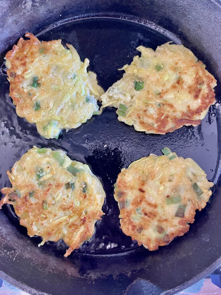 Golden sourdough zucchini fritters in a cast iron skillet.