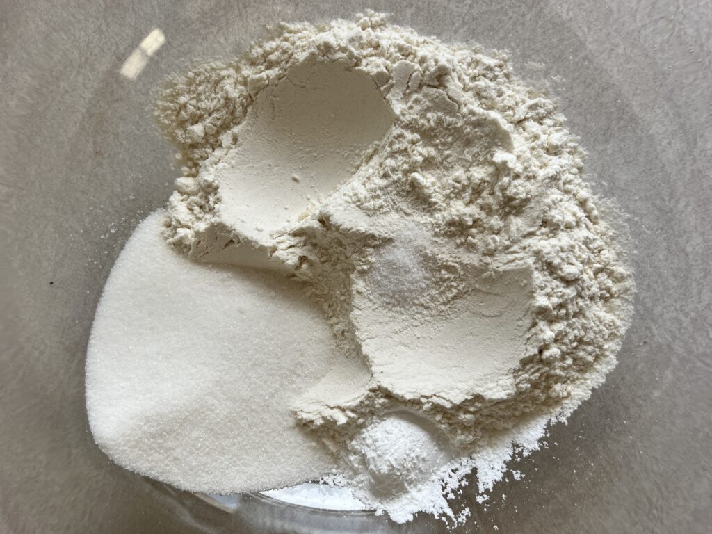Flour, sugar, baking powder, vanilla, salt in a bowl for buttermilk pancakes. 