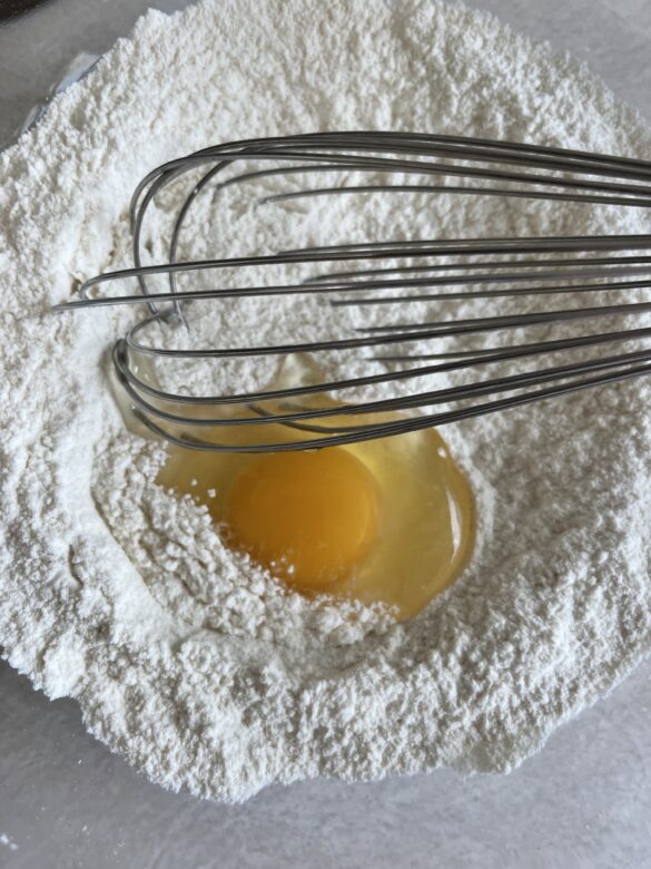 Egg cracked into a flour mixture for buttermilk pancakes.