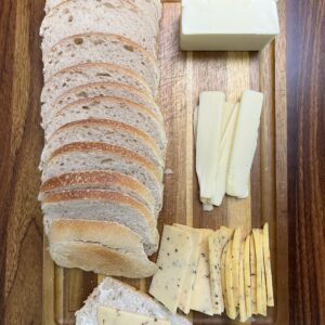 Sourdough sandwich loaf with butter and cheese on a cutting board.