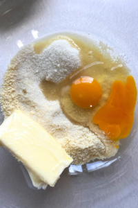 Almond flour, eggs, sugar, and butter in a bowl.