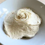 Cream cheese frosting being whipped with browned butter and powdered sugar.