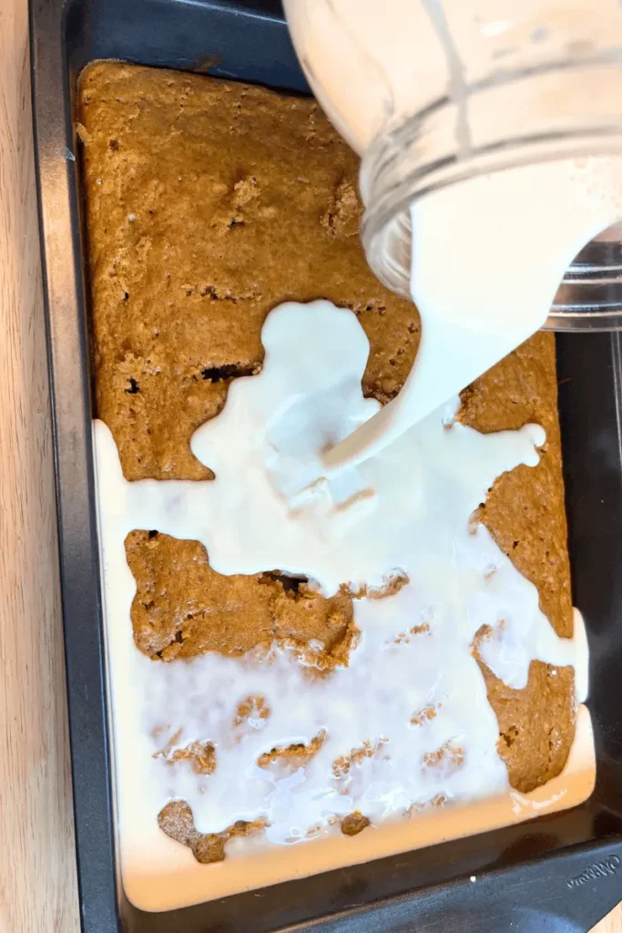 Tres leches mixture pouring over pumpkin cake. 