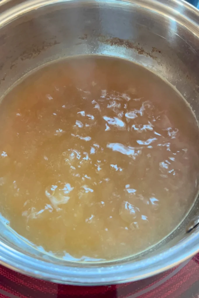 Reducing apple cider in a pot for Sourdough Apple Cider Muffins.