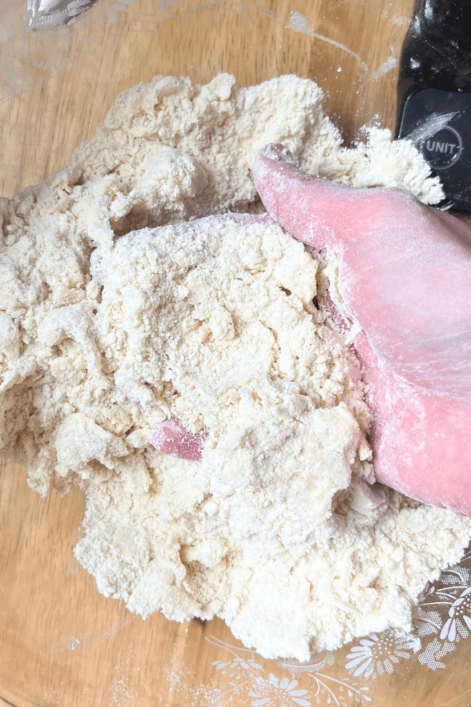 Hand mixing dry ingredients with cold butter.