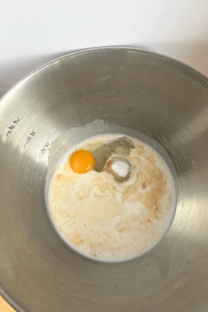 Active sourdough starter, warm milk, sugar, egg, and vanilla extract in a large mixing bowl. 