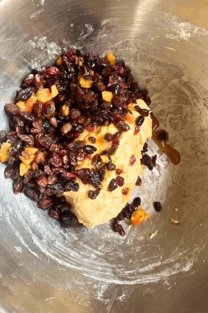 Sourdough stollen bread dough with dried fruit in a large mixing bowl.