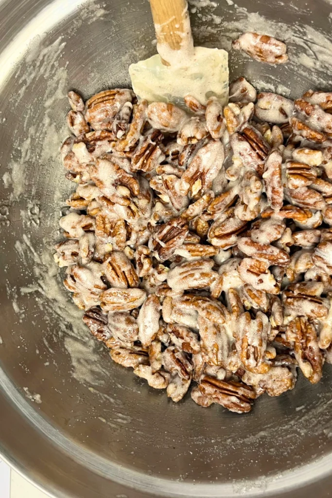 Tossing pecans in frothy egg white and sugar mixture to coat evenly.