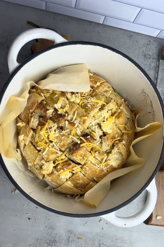 Garlic butter and cheese filled sourdough boule baking again in a Dutch oven.
