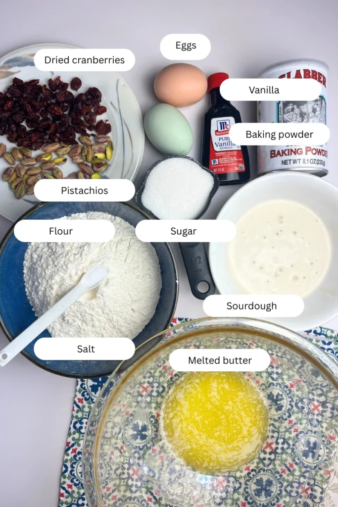 Ingredients for cranberry pistachio sourdough biscotti including sourdough discard, flour, sugar, eggs, cranberries, and pistachios.
