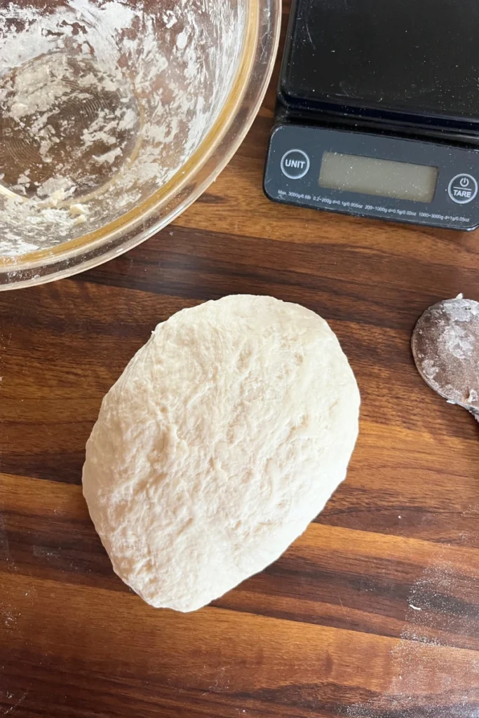 Sourdough starter, flour, and water being mixed together to form stiff bagel dough.