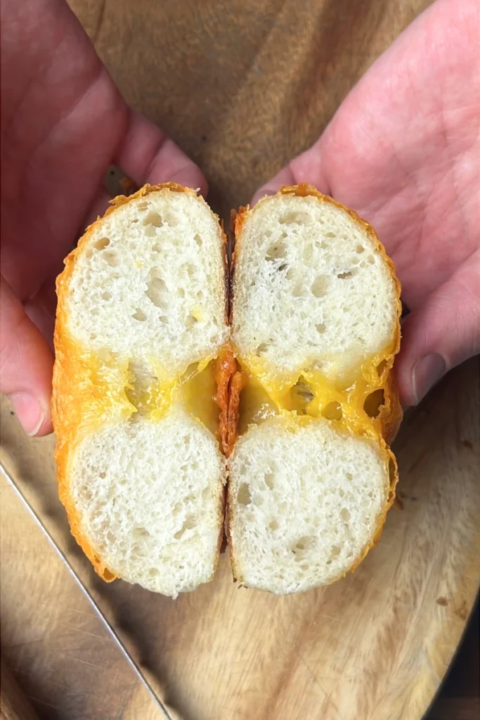 Sourdough bagel cut in half after proofing overnight in the refrigerator, showing airy, chewy interior.