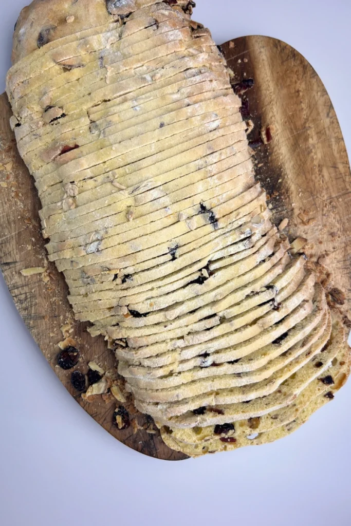 7 Slicing baked sourdough cranberry almond thins logs into thin cookies.