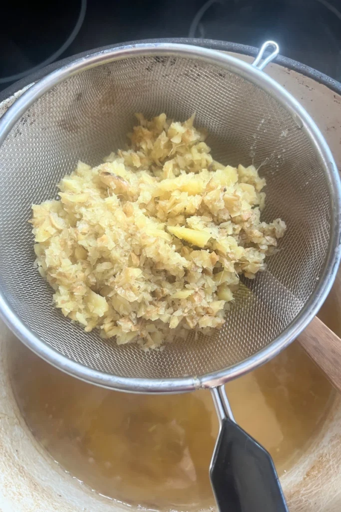 5 Straining ginger mixture for ginger honey lemon chews to remove pulp.