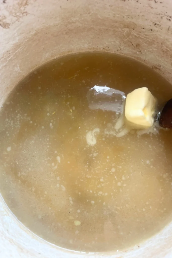 6 Adding butter to boiling ginger honey mixture for ginger honey lemon chews.