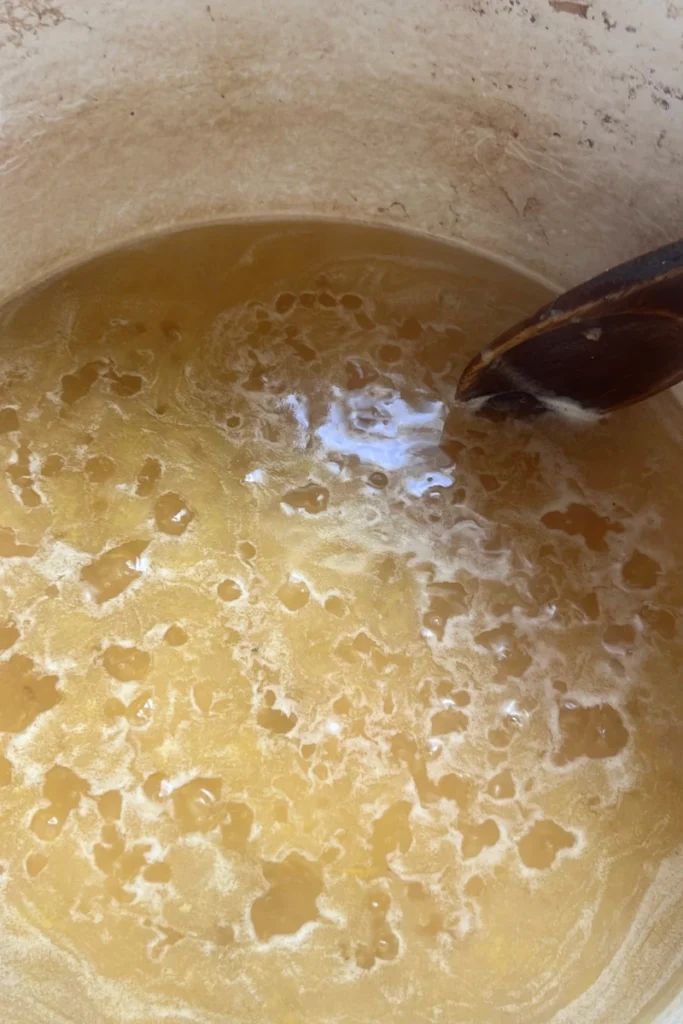 Boiling ginger honey mixture in saucepan for ginger honey lemon chews.