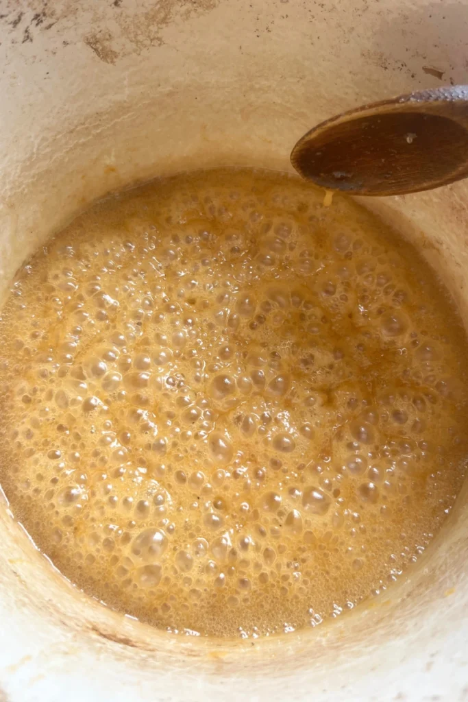 Butter melting into hot ginger honey mixture for homemade ginger chews.